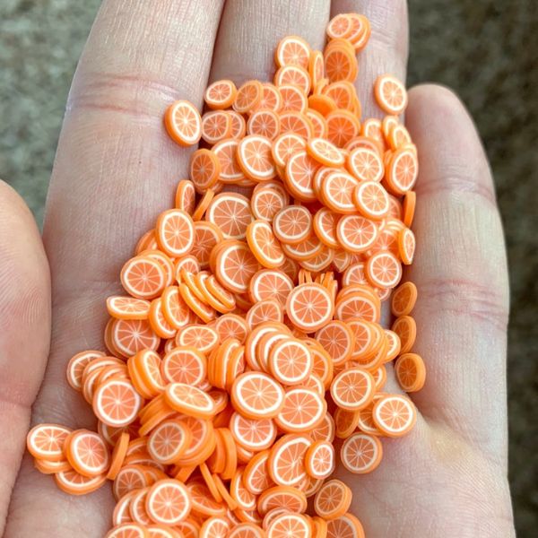 Several bunch of Miniature Resin Orange Slices on a hand.