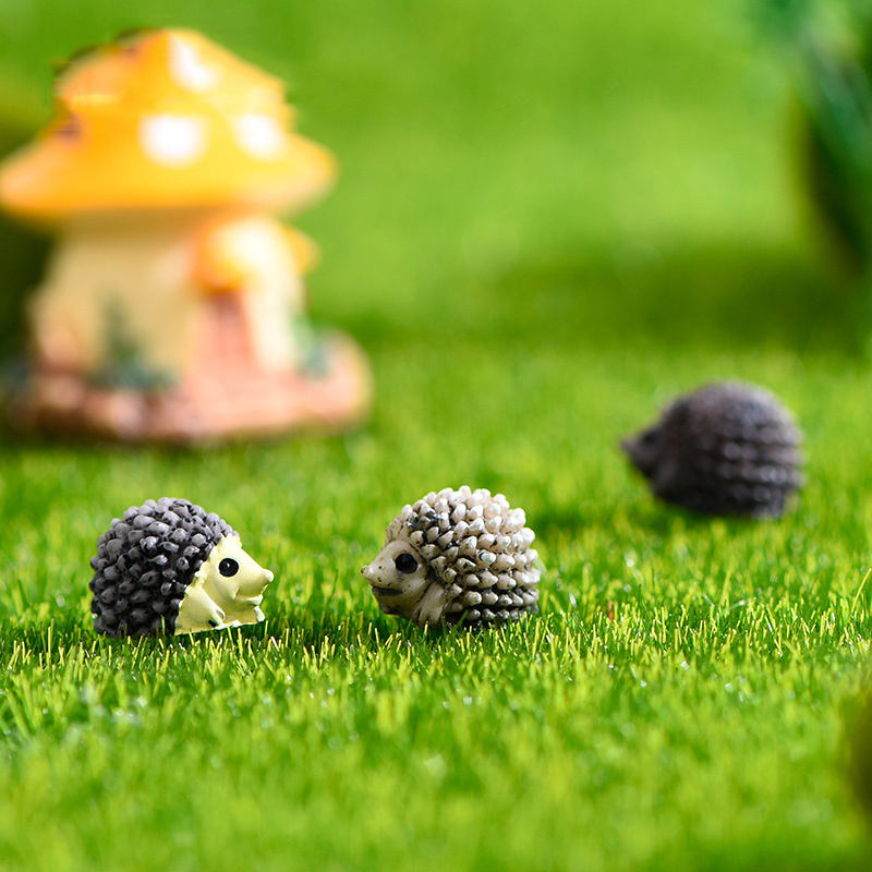 Miniature Porcupine figures placed on glass with a fairy garden background.