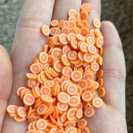Several bunch of Miniature Resin Orange Slices on a hand.