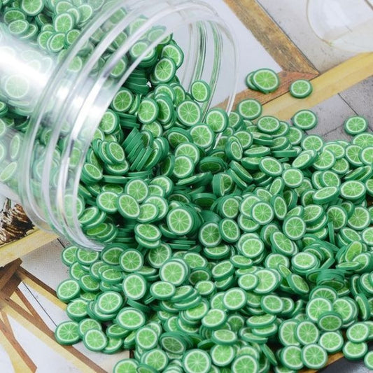 Several Miniature Polymer Clay Green Oranges fell out of a transparent jar.