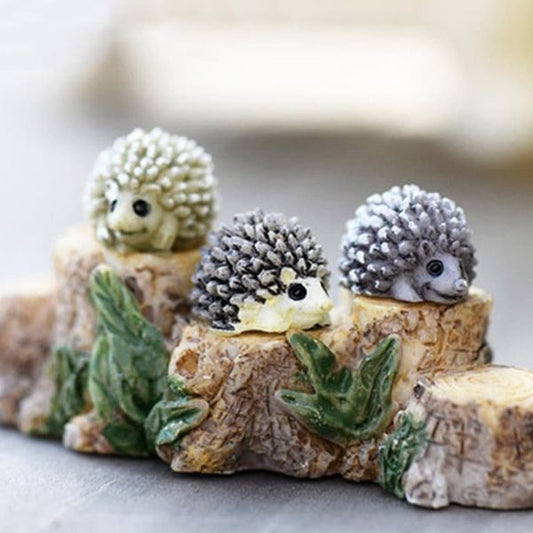 Small and cute three different colors Miniature Porcupines on a miniature tree trunk with a blurred background.