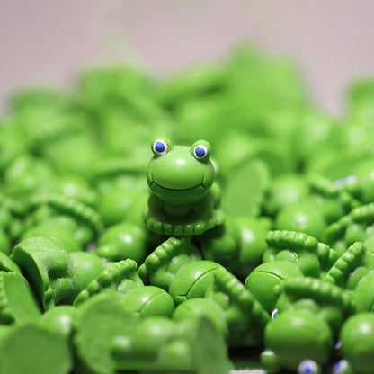 A cute Miniature Toy Frog kept on another Miniature Toy Frog with several similar Miniature Toy Frog in the background.