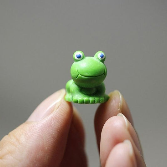 A hand holding cute Miniature Toy Frog.