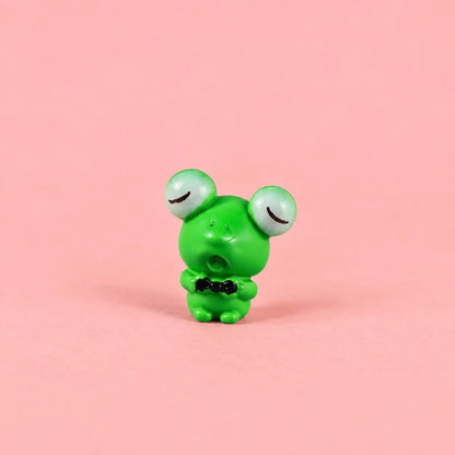 Miniature Resin Mini Frog Assorted (1pc) displayed on a pink background