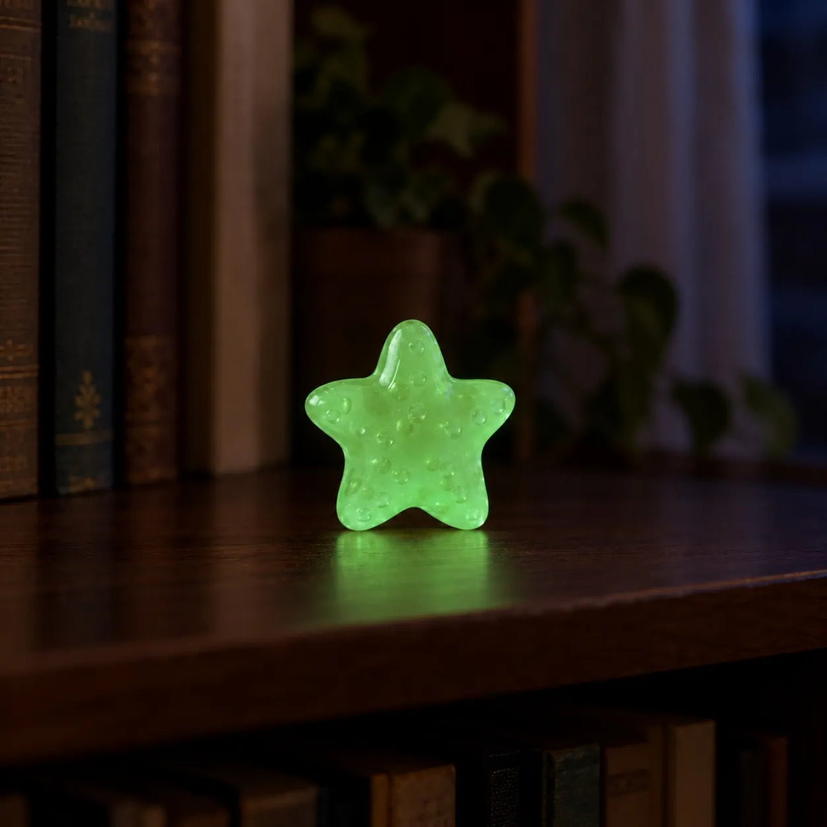 Miniature Glow Starfish Assorted (1pc) glowing on a dark wooden shelf